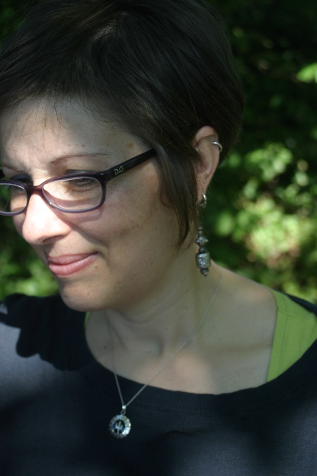 a woman wearing glasses looking down at soing