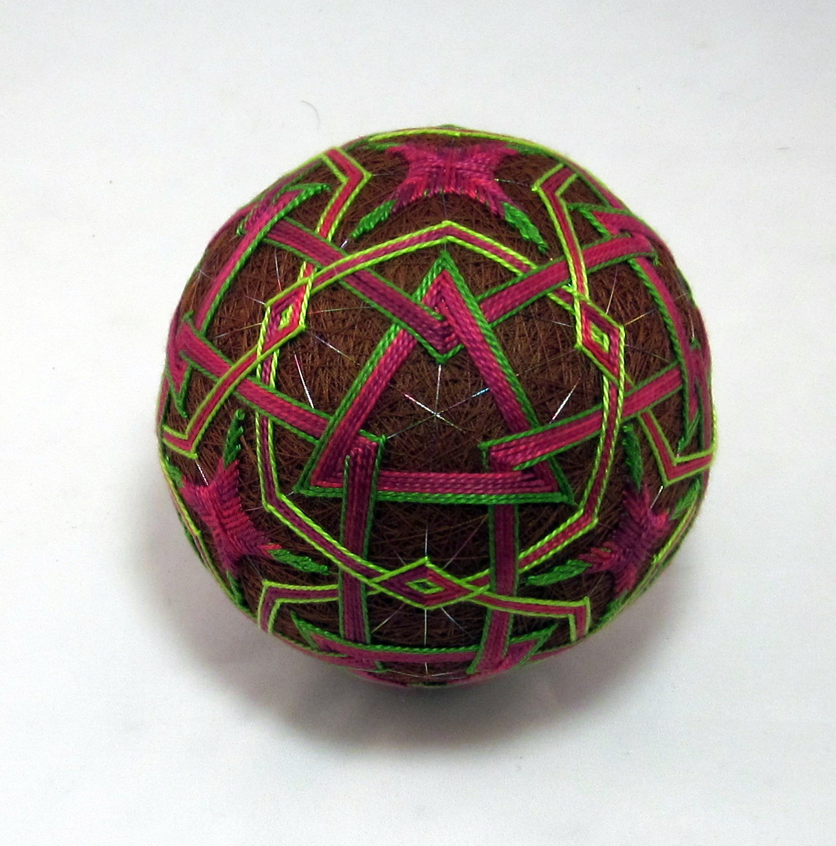 a purple and green colored ball with gold thread