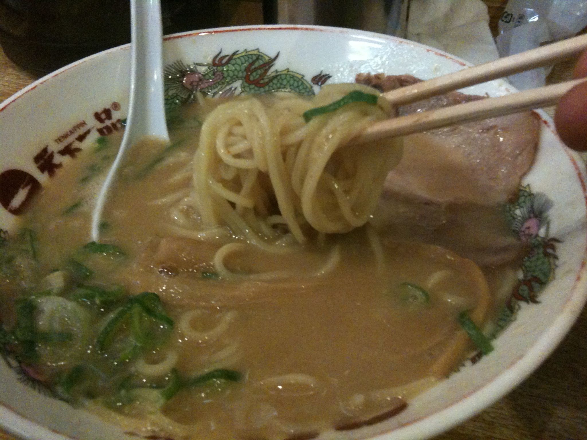 someone holding chopsticks over a bowl of noodles