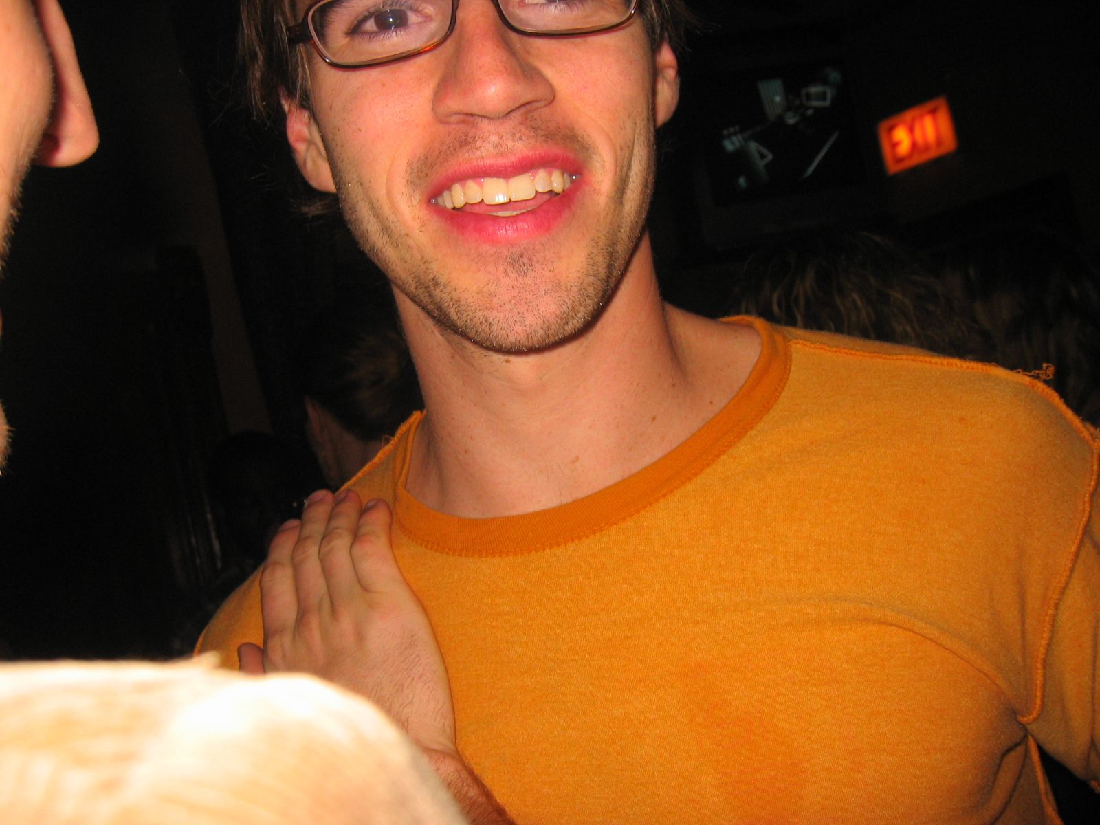 smiling young man in glasses holding his neck