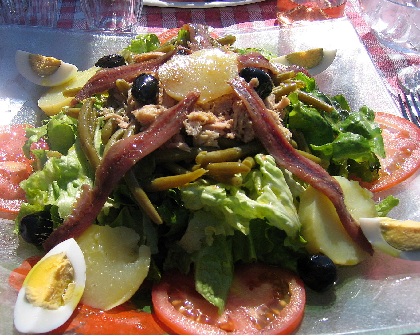 a salad with meat, cheese, and other vegetables is sitting on a plastic plate