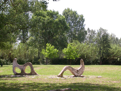 three wooden sculptures in an open area surrounded by trees