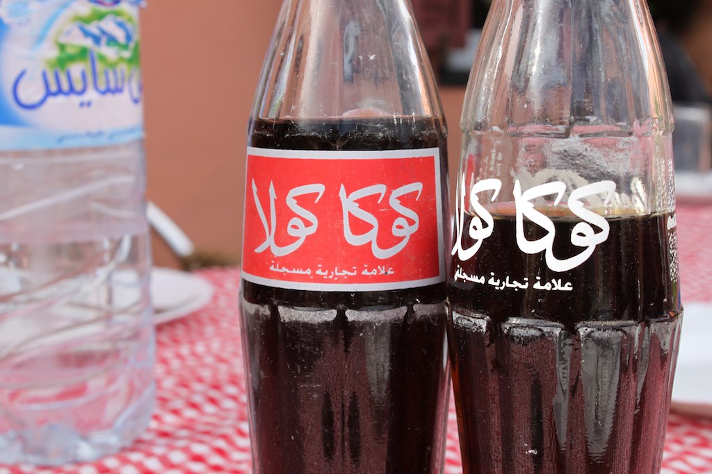 two empty soda bottles sit on a red tablecloth