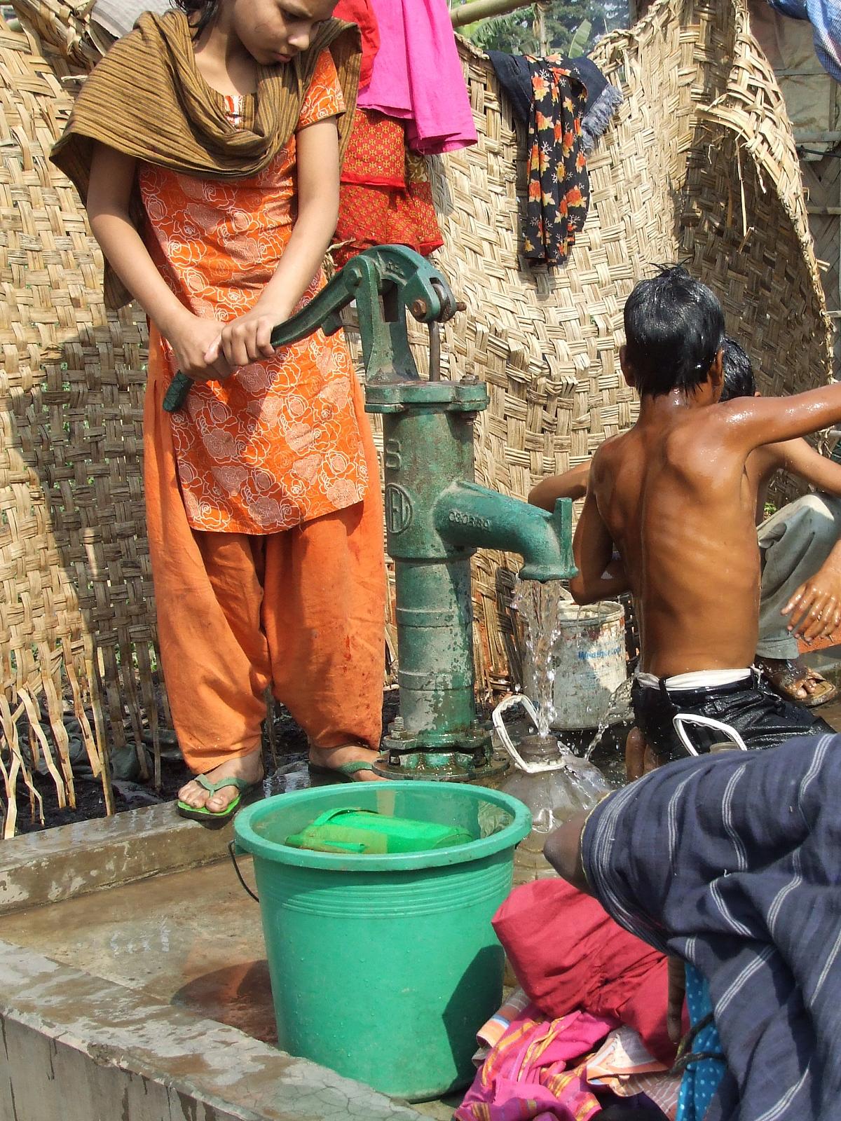 people in india wash their clothes with a water pump