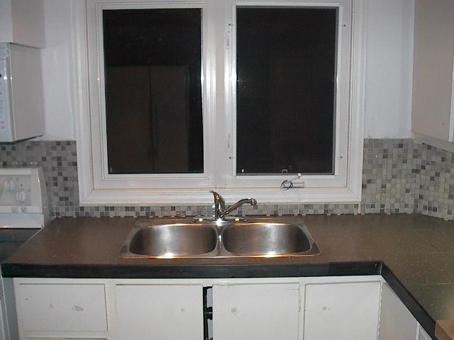 a kitchen sink under two open windows