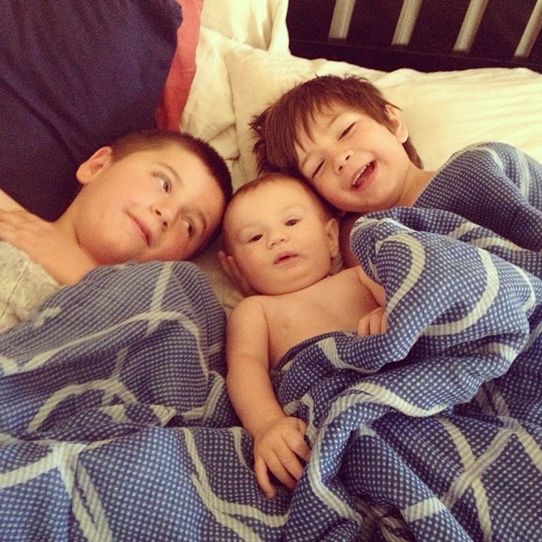 a family that is laying down in bed