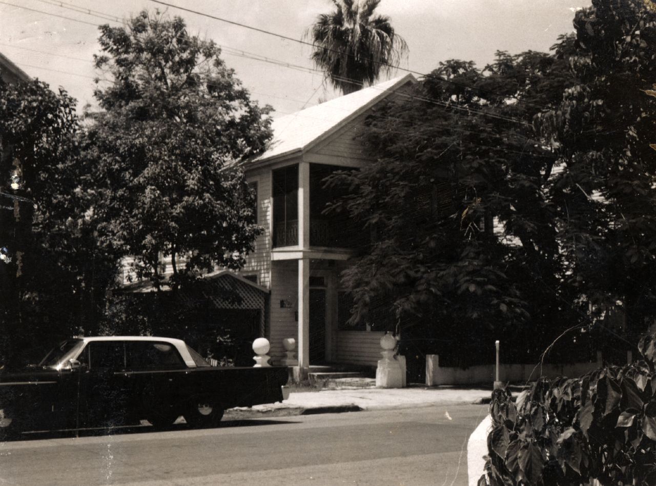 black and white pograph of a house with car parked in front