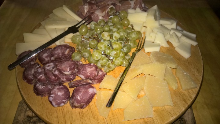 a plate of meats, cheese and cheese tongs