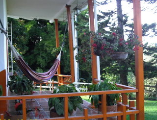 two hanging chairs are in the shade on an outside porch