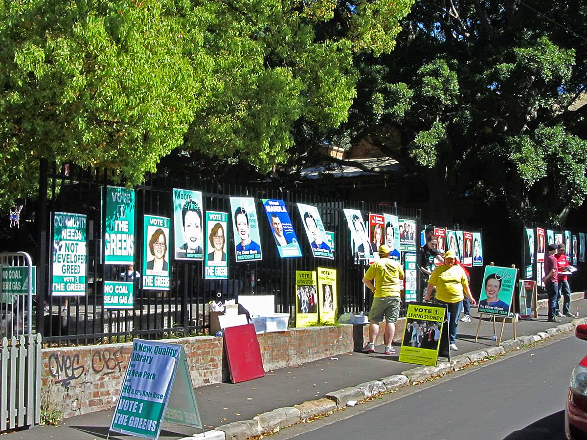 posters and flyers on the sides of a road next to trees