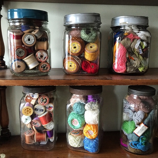 a group of jars with thread and various items in them