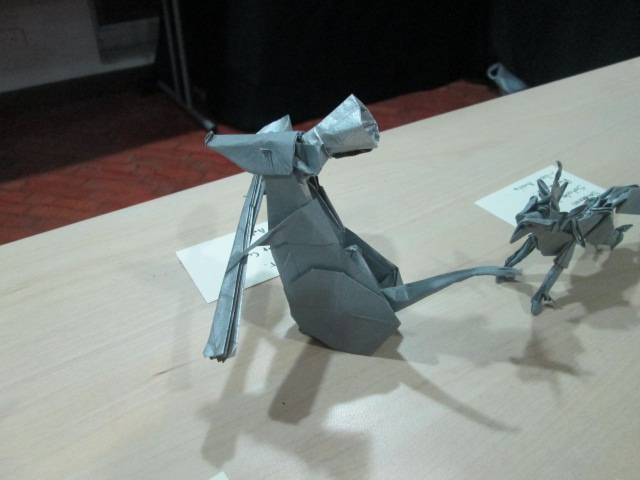 the origami mouse is gray and the origami cat looks like it is sitting on a table