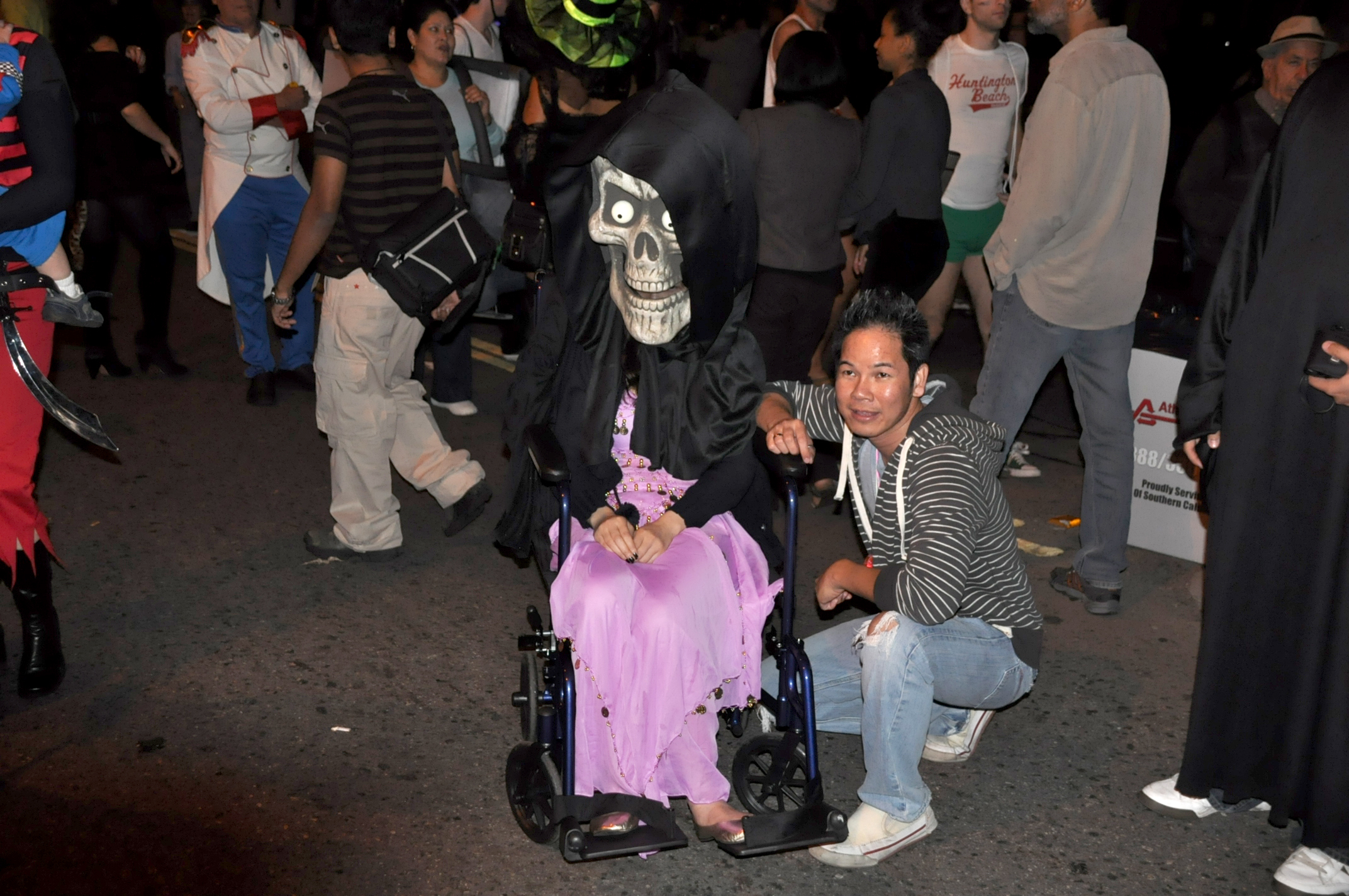 a man dressed as grim in costume poses next to a skeleton