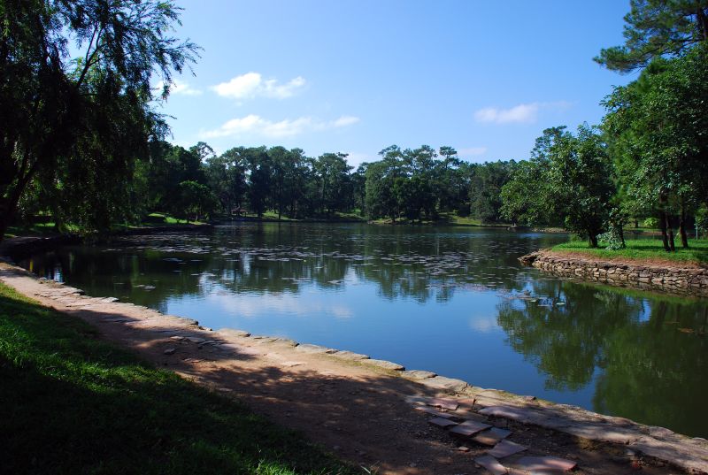 a lake surrounded by grass and trees in the foreground