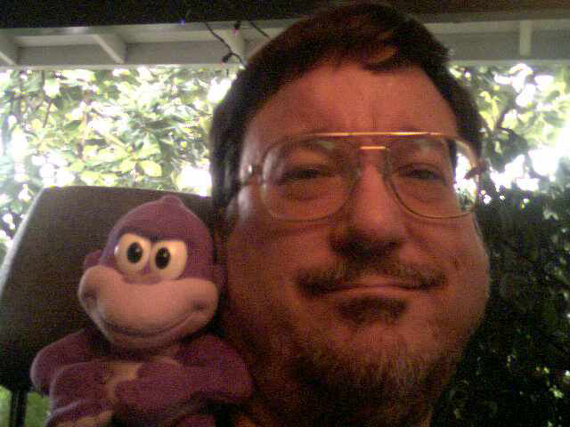 a man in glasses holding up a monkey stuffed animal