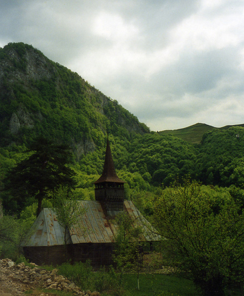 an old rusty wooden church on a hill near the woods