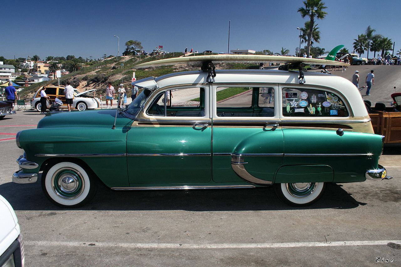 an antique car is parked with surfboards on top