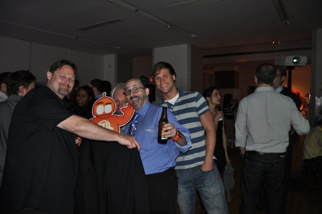 three men and a woman standing together at a party