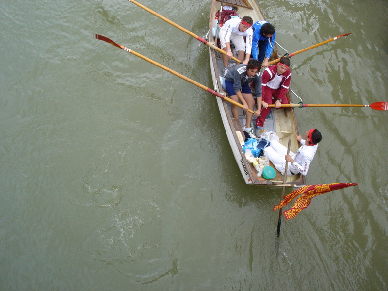 group of people in red shirts rowing a boat with two oars