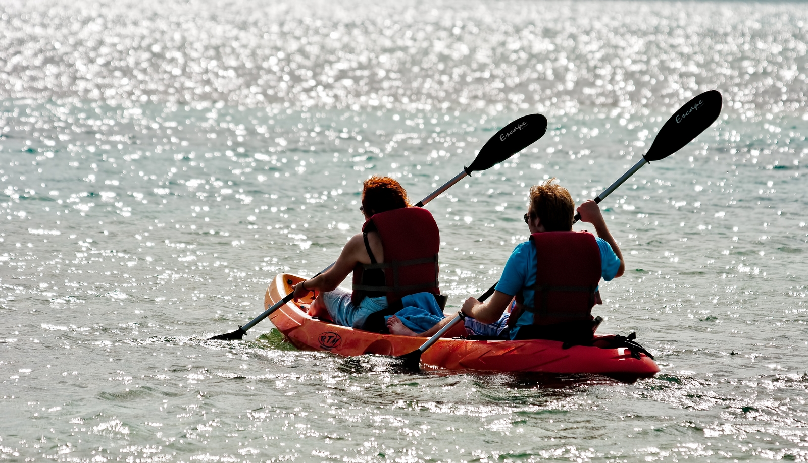 two people are in an orange kayak going down the water