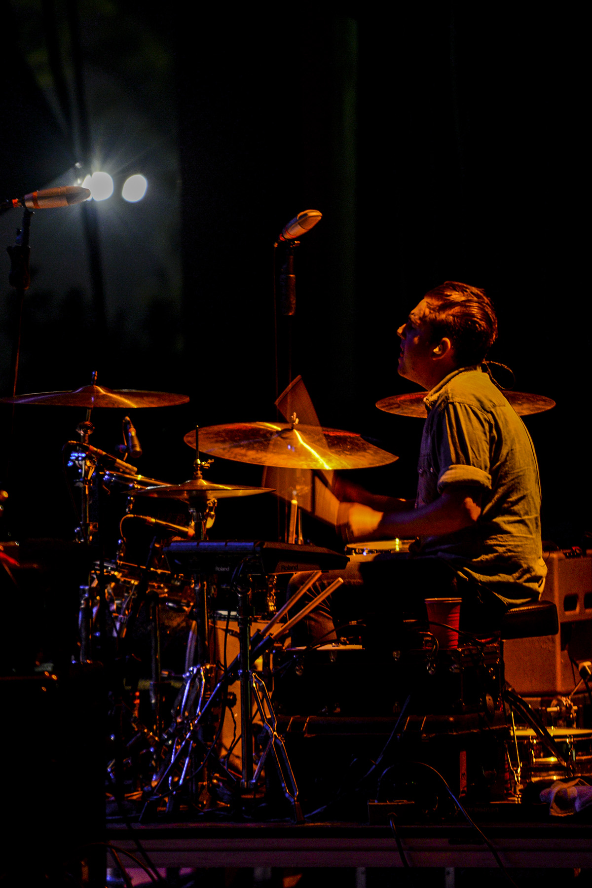a man playing the drums on stage in a darkened room