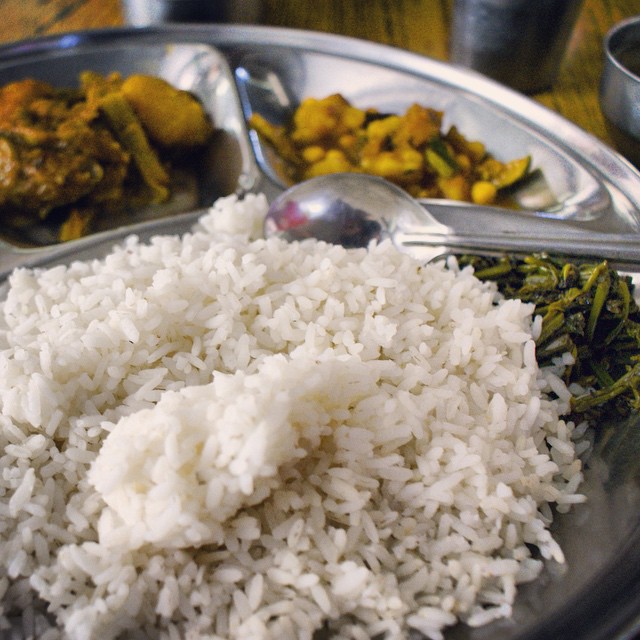 a bowl of rice and broccoli with some serving spoons