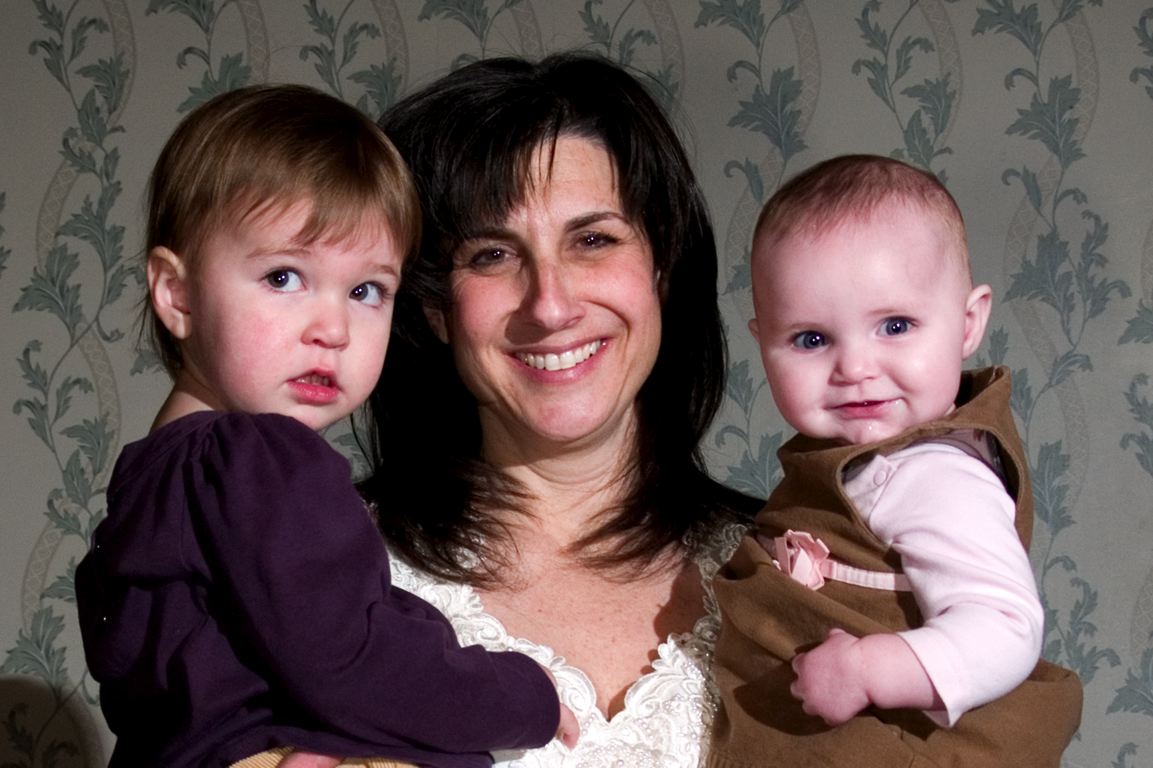 woman holding two children and smiling at camera