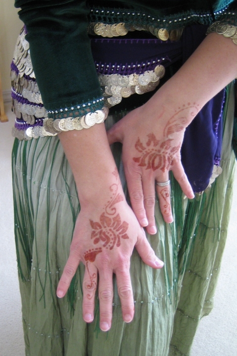 hands with hendign painted on them and beads around