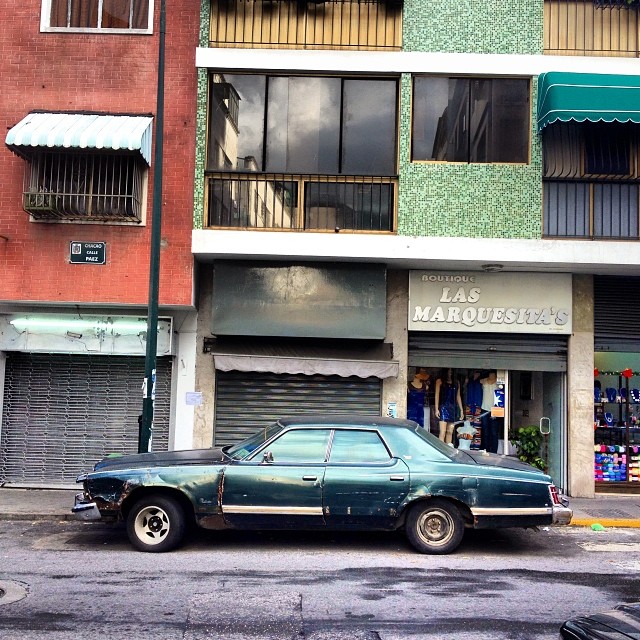 a old car is parked in front of a multi - story building