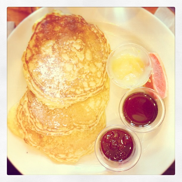 pancakes, orange juice, and jam on a white plate