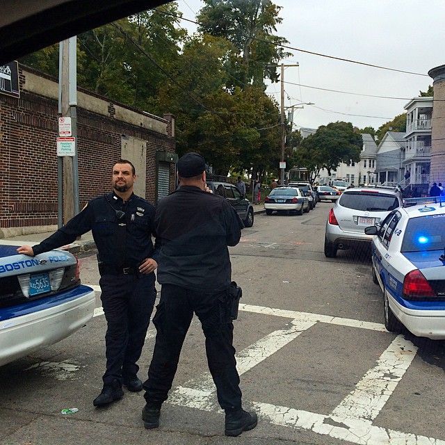 two officers stand near a police car on the street