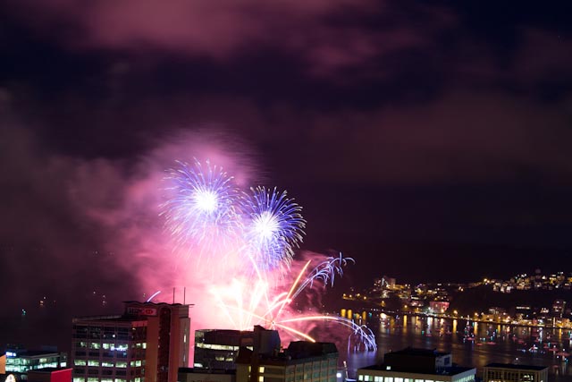 a bunch of fireworks light up the night sky above the city