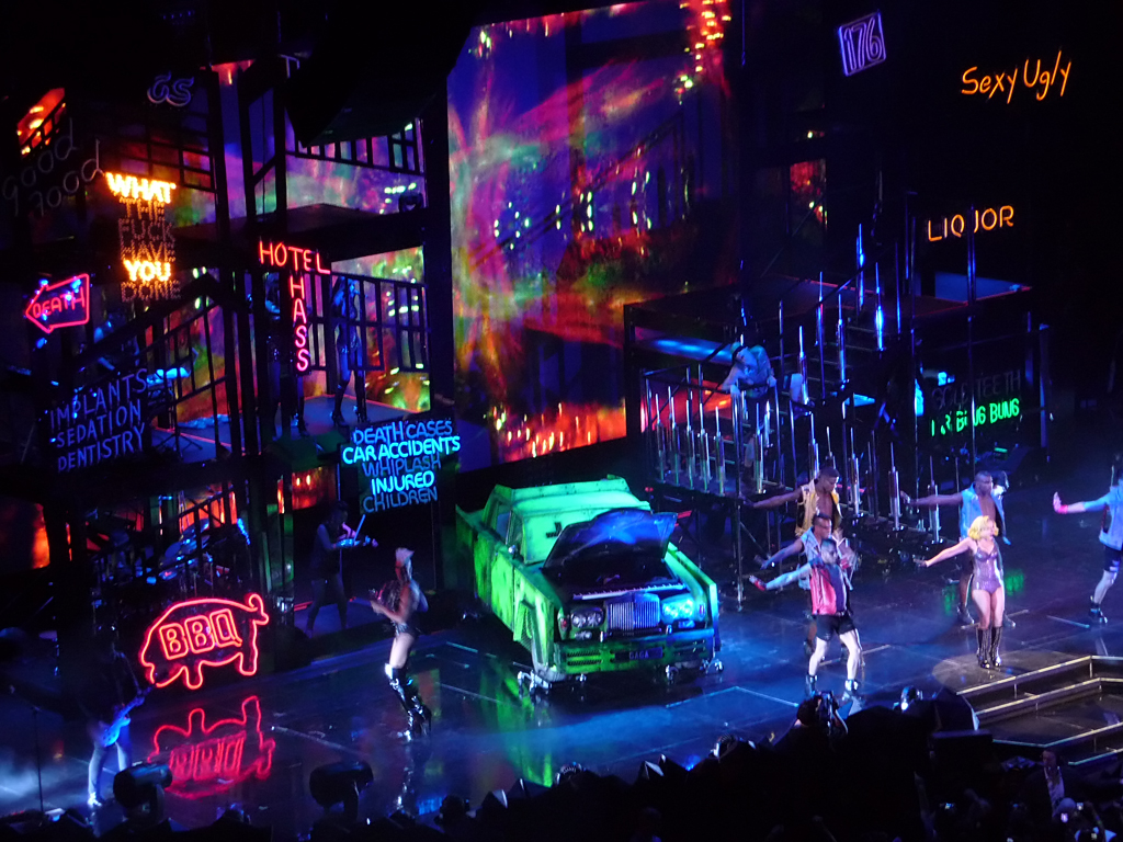 a car sitting in front of a set of colorful neon signs