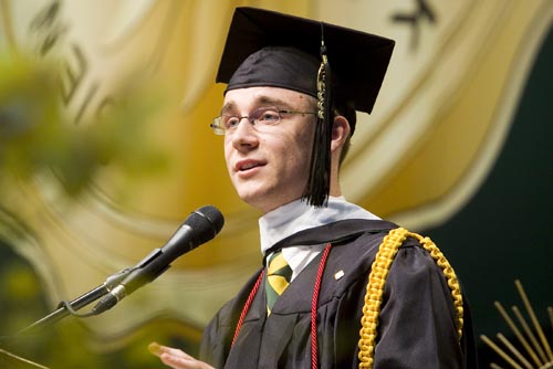 a man at graduation speaking at a microphone