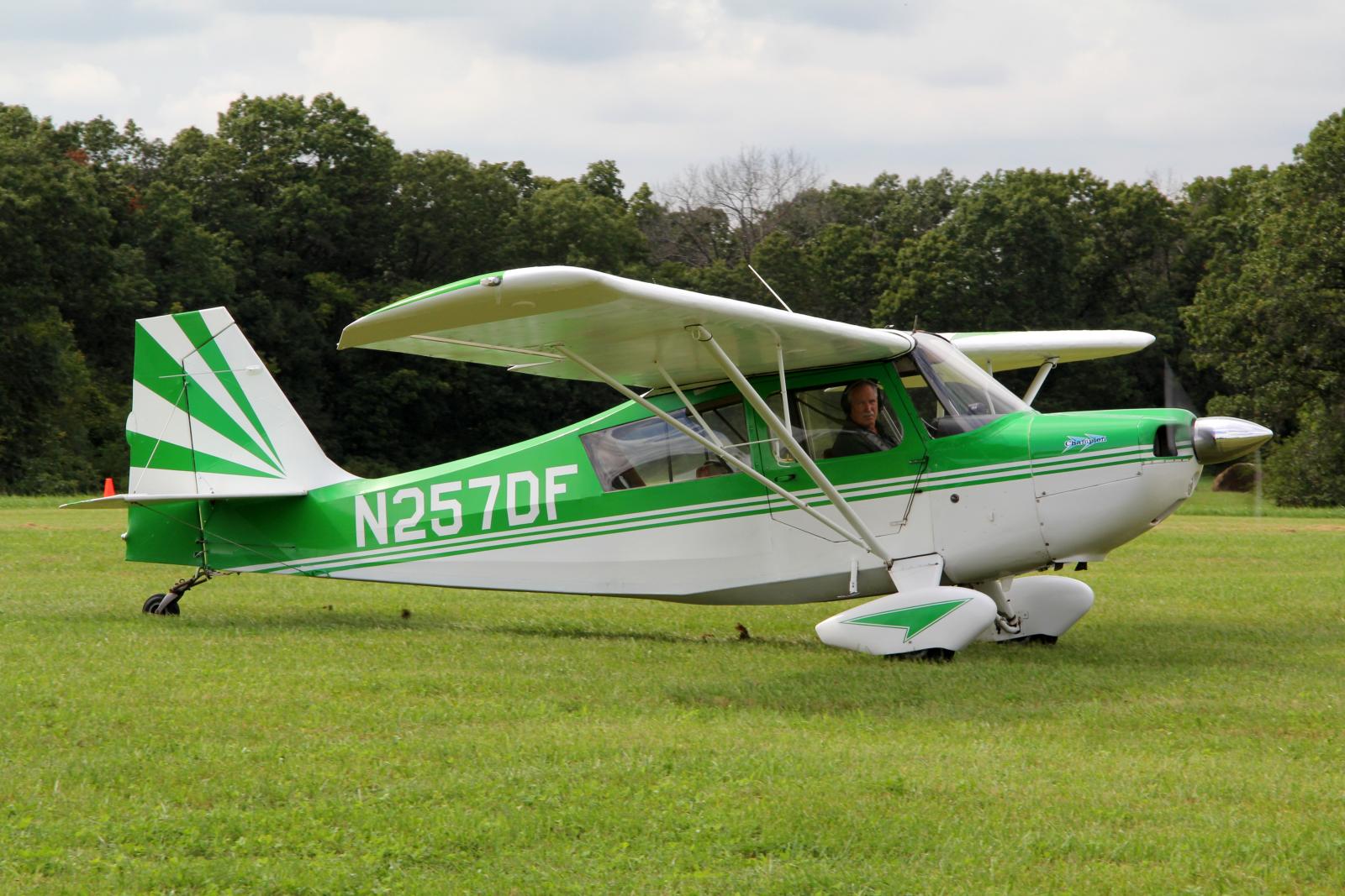 a white and green plane with a green pilot in the cockpit