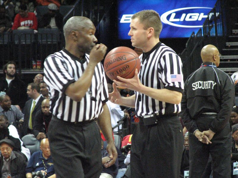 a referee holding a basketball with a basketball on his finger