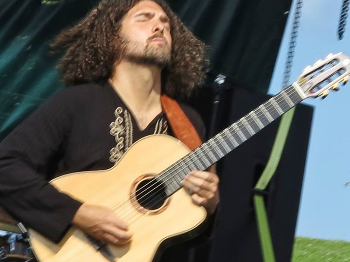 a man with long hair is playing a guitar