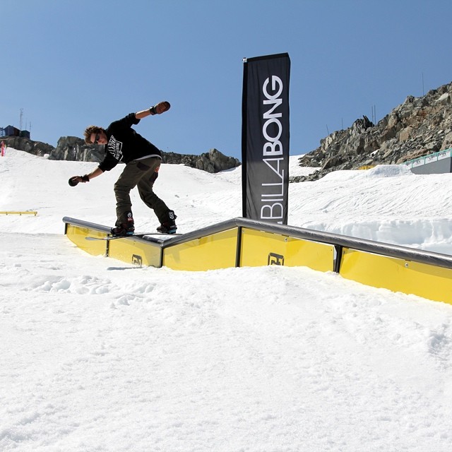 the man is snowboarding on the rail in the snowy field