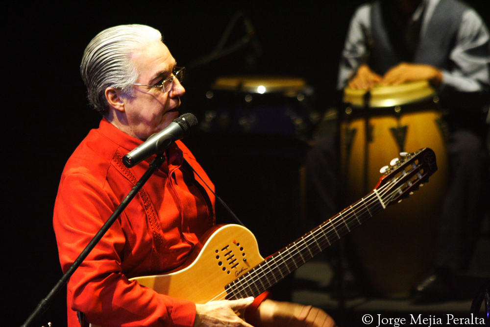 man with glasses on singing and playing guitar