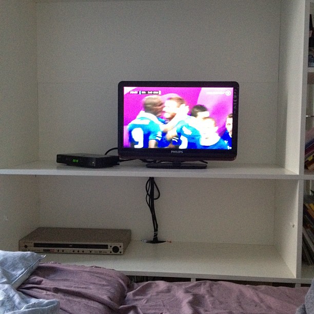 a flat screen television mounted on top of a white book shelf
