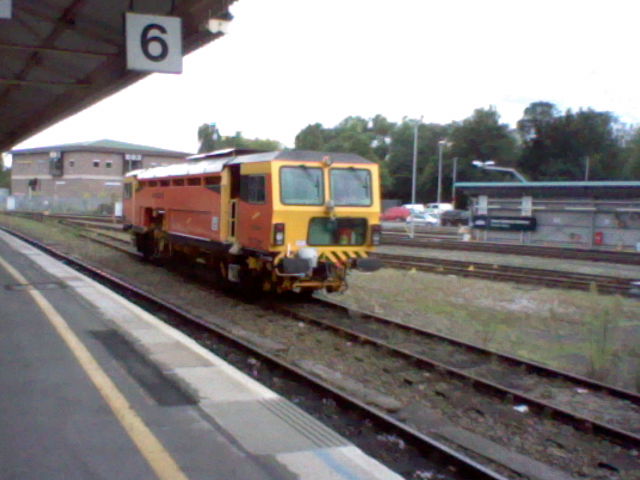 train passing by with green and red train car on track