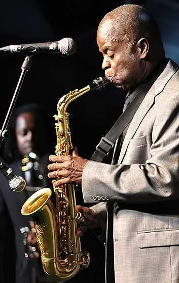 a man in grey suit holding a saxophone