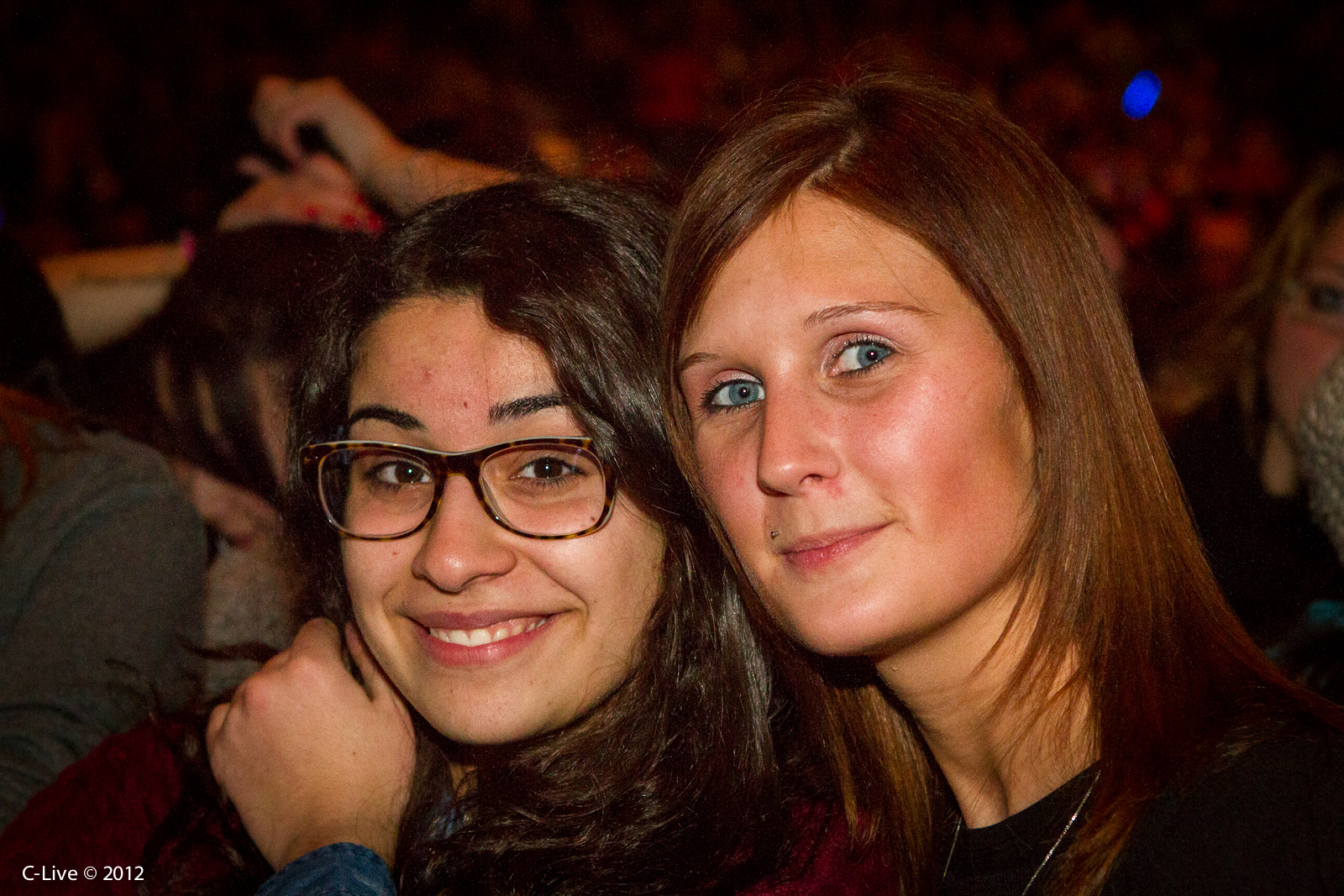 two beautiful young women standing next to each other at a concert