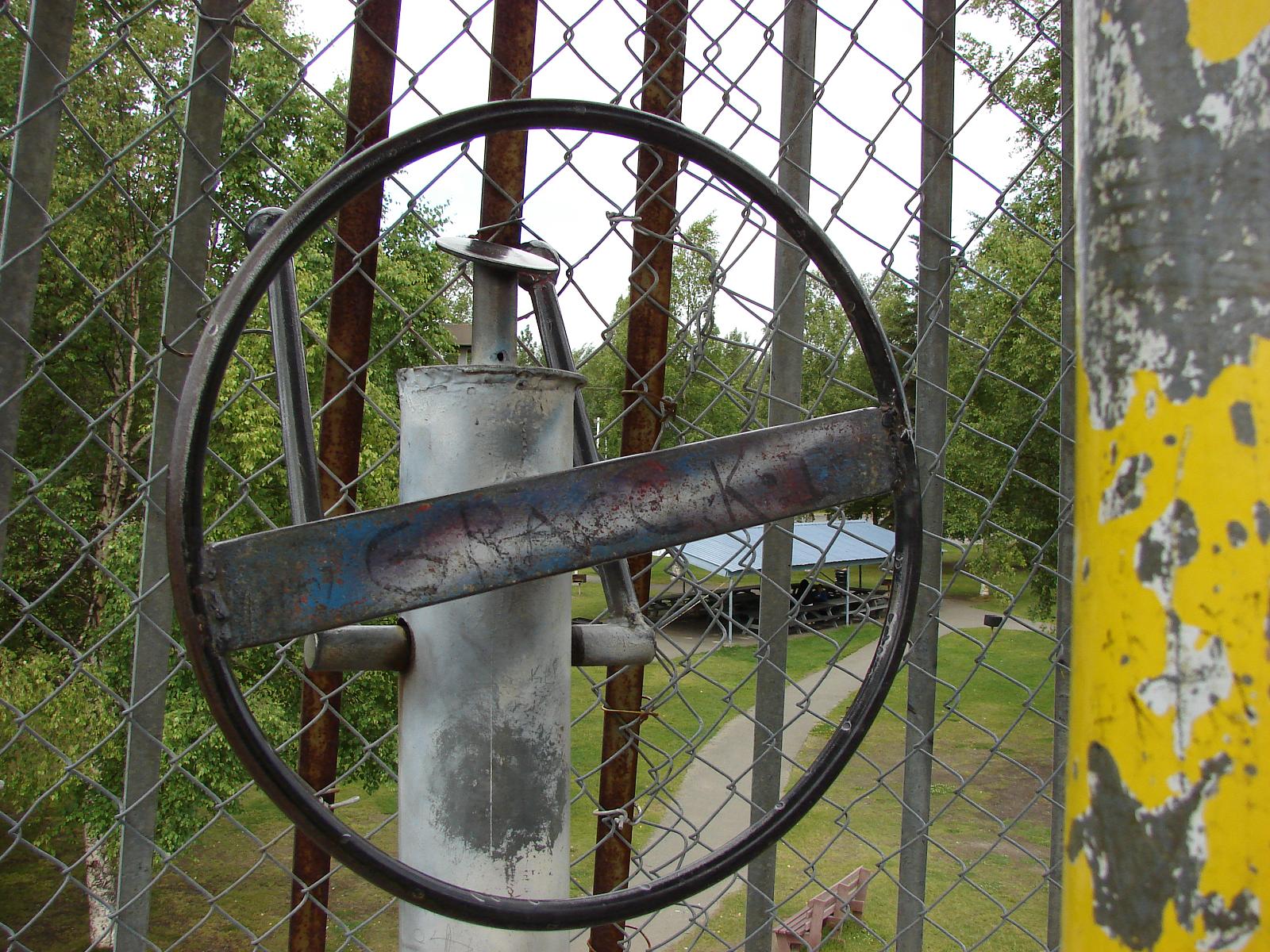 a rusty steel object stuck behind a fence