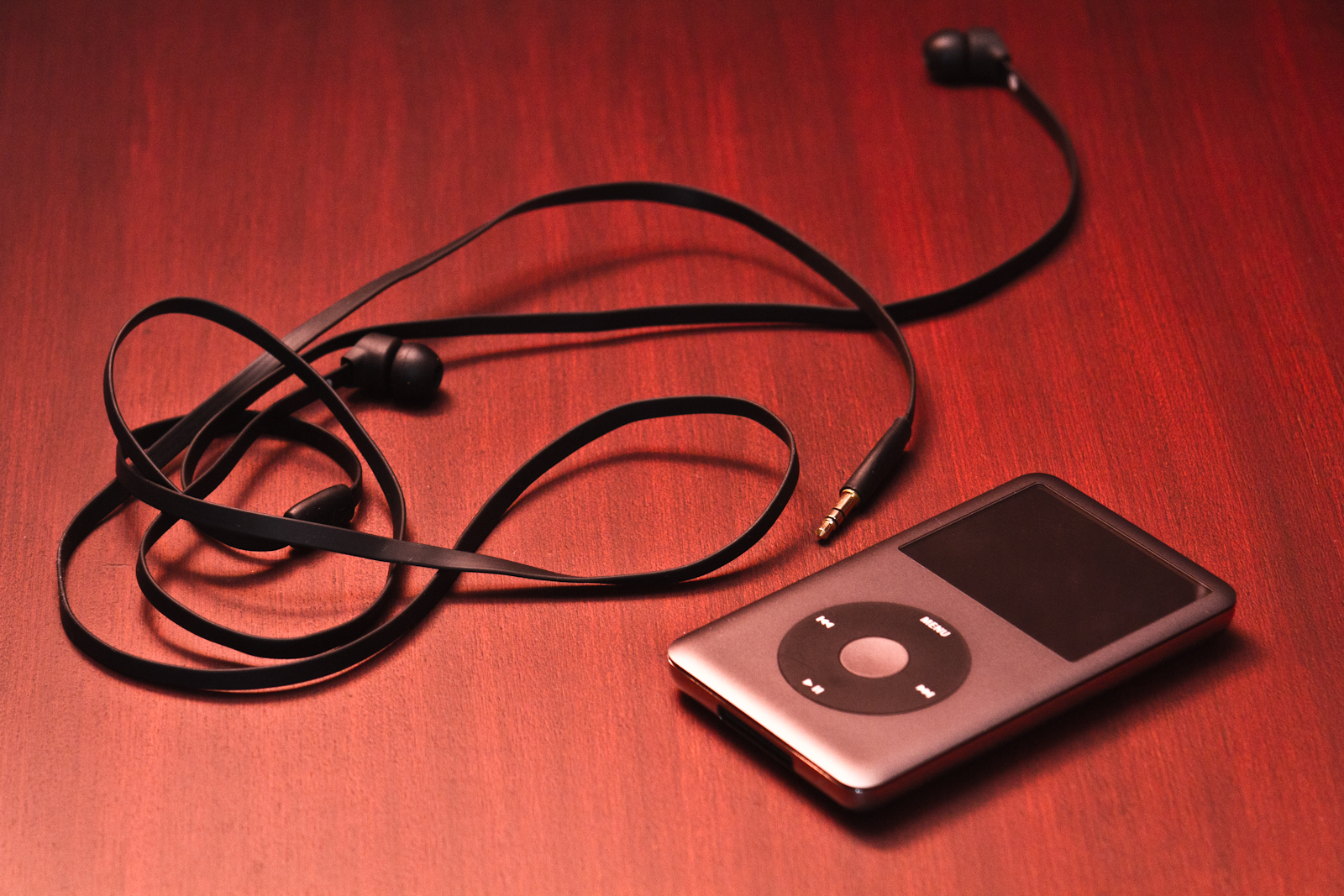 a mp3 player with ear buds and earpieces on a red background