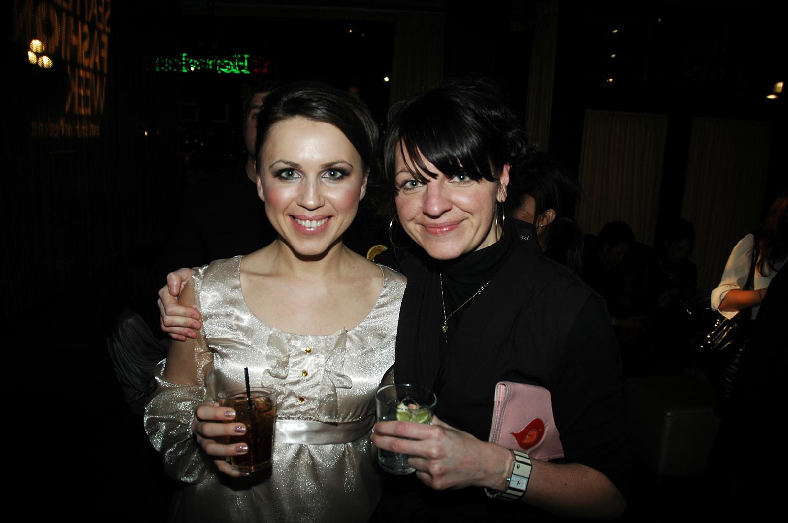 two women pose for a picture with their drinks