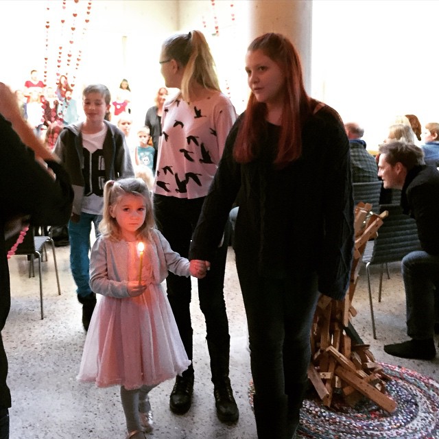 a group of people are gathered around a little girl holding a candle