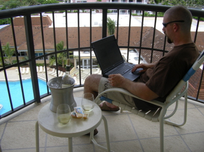 a man sitting in a chair on top of a balcony with a laptop