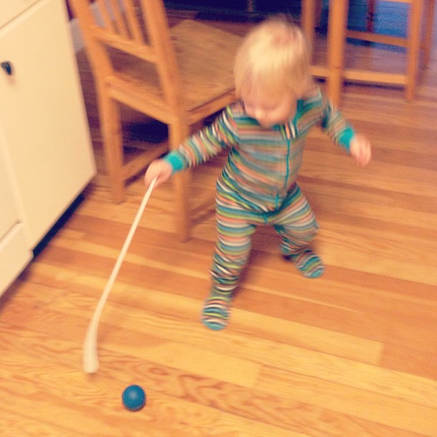 a baby reaching forward for a toy on the floor