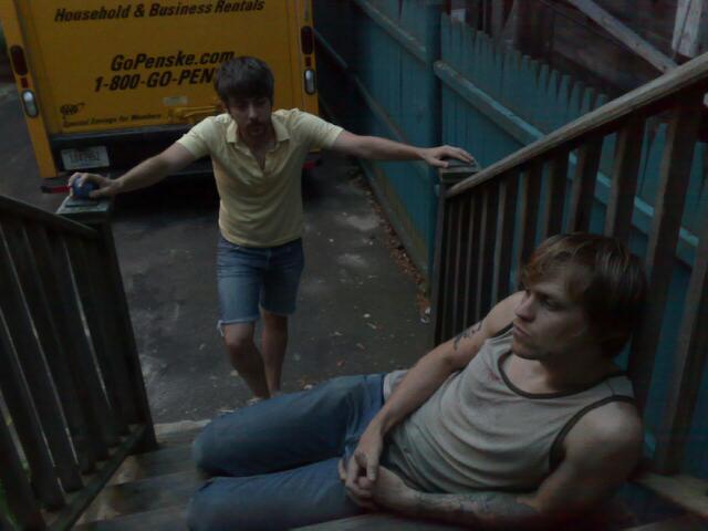 two men on the stairs of a train station, one with a broken hand